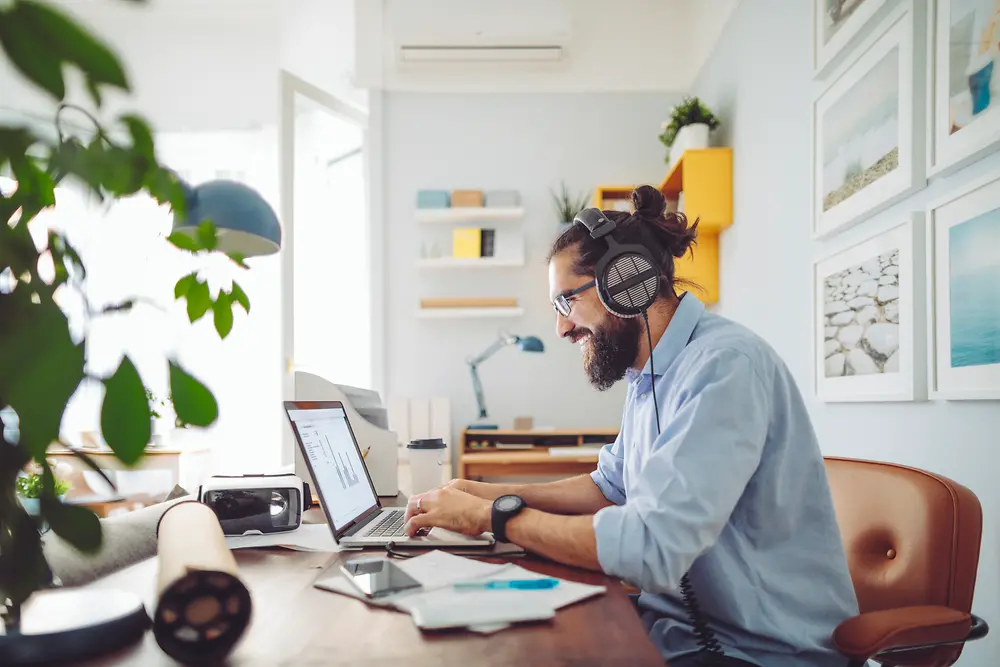 Hombre con auriculares sentado en el escritorio de trabajo 